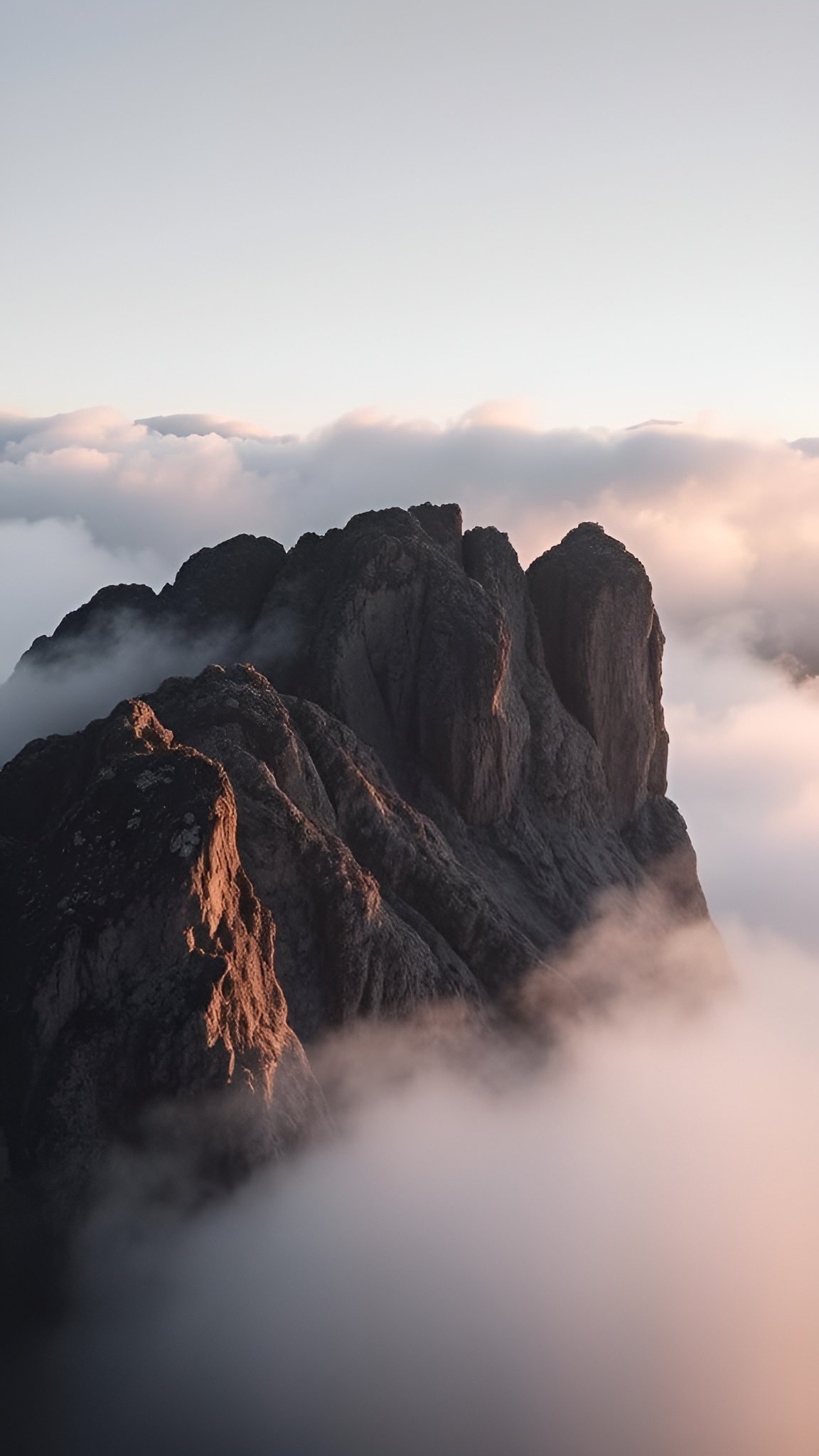 Epic mountain peak piercing through a sea of clouds at sunrise